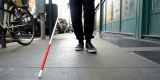 失明、定位、城市。一个盲人拄着拐杖走在街上