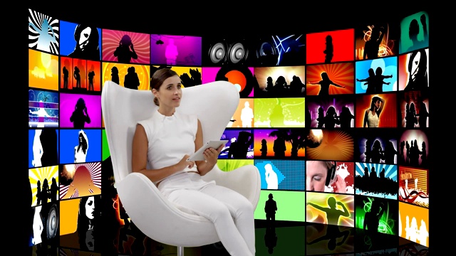 坐在白色椅子上的女人，屏幕上放着视频