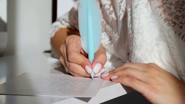 特写的女孩的手拿着一支蓝色的笔，并在笔记本上写。