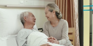 慈爱的亚洲老妇人在医院病房探望丈夫