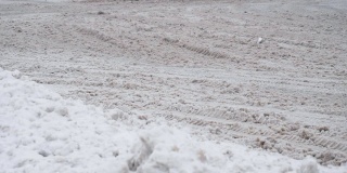 带有冬季轮胎的越野车在白天下雪的雪地上行驶。车轮在慢动作的特写。恶劣的天气导致交通堵塞，暴风雪。危险的旅行。地面上有透明的黑色冰