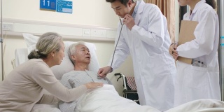 年轻的亚洲医生在医院病房检查老年病人