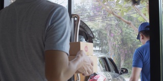 亚洲快递员携带纸包裹盒子交付给客户。邮政投递服务的概念。慢动作4k超高清。