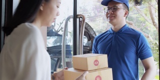 亚洲送货男子携带纸包裹盒子交付给女性客户。邮政投递服务的概念。慢动作4k超高清。