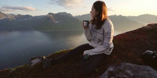 在Senja山上坐着喝茶的女人