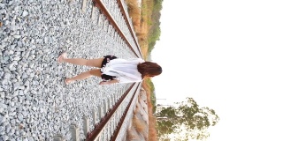 年轻的亚洲女游客独自走在铁轨上，极端的地形场景，垂直格式的视频智能手机