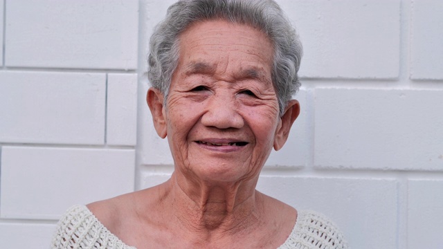 白色墙壁背景上微笑的亚洲老年妇女的肖像。肖像，老年人，退休，人，生活方式，医疗，保健和医学概念。高级的肖像