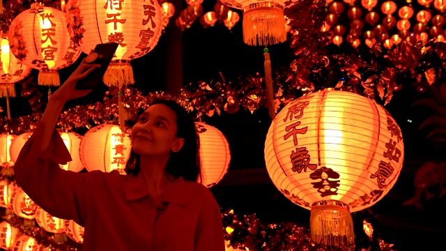 女人拍照的许多中国灯笼在神社。