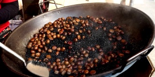 Chestnuts roasting in pan with hot black sand.