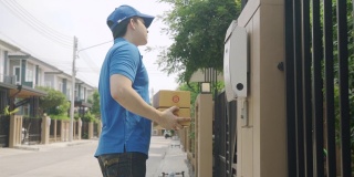 亚洲快递年轻男子身穿蓝色制服，微笑着拿着一堆纸箱在前屋村与复印空间。广告，商业，交通概念。