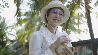 年轻女子在公园里喝椰子汁视频素材模板下载