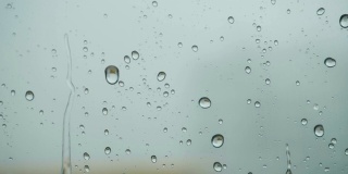 雨点落在窗外的玻璃上。关闭了。缓慢的运动。雨落在玻璃上。雨滴落在车窗背景上。秋天天气不好。