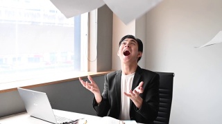 一位亚洲华裔年轻白领坐在办公室的椅子上，把文件扔向空中，心情沮丧，情绪紧张视频素材模板下载