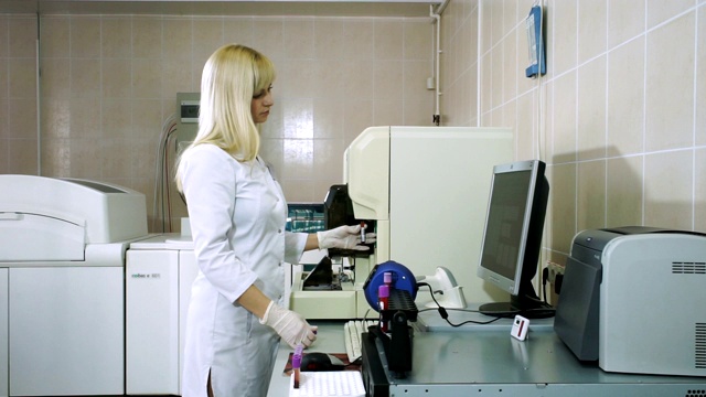 女性实验室助理在现代设备下分析血样。高清
