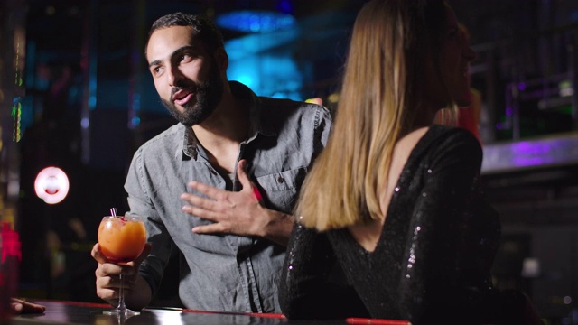 一个快乐的中东青年在夜总会喝着鸡尾酒和酒保聊天。快乐的长胡子帅哥在迪斯科舞厅晃悠。生活方式、娱乐、快乐。电影4k ProRes总部