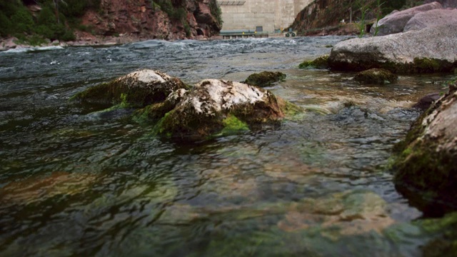 倾斜向上的镜头，绿色的河流在石头上流淌，火焰峡谷大坝在犹他州的背景