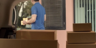 一名亚洲快递员，在快递车的后面检查和搬运纸包盒。邮政投递服务的概念。慢动作4k超高清。