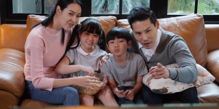 周年快乐的亚洲家庭一起坐在家里的客厅里。父亲和母亲放松与儿子和女儿。白人家庭观念，教育，小学。