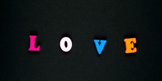 “爱”字由彩色木制字母组成。丰富多彩的文字循环。定格动画
