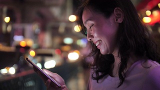 一名女子在夜街用智能手机进行社交媒体视频素材模板下载
