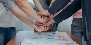4K UHD近距离:集团快乐的年轻亚洲员工加入堆栈手一起在头脑风暴会议在办公室。休闲业务与创业团队社区庆祝的概念。