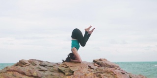 亚洲女人用一个苗条的瑜伽在山的背景天空和海洋，健康积极的生活理念