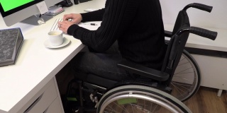一个坐在轮椅上的经理，一个不能在他工作的电脑前行走的年轻人，慢动作