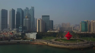 阳光灿烂的日落青岛市区著名的海湾广场航拍全景4k中国视频素材模板下载