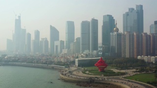 阳光灿烂的日落青岛市区著名的海湾红纪念碑广场航拍全景4k中国视频素材模板下载