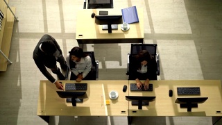 在呼叫中心，男经理协助女接线员的俯视图视频素材模板下载