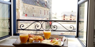 窗台上的法式早餐托盘。羊角面包，奶酪，果汁，果酱，圣女果和法棍面包