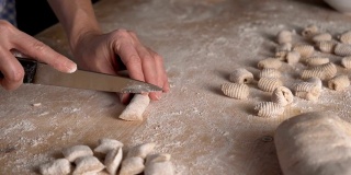 用全麦面粉制作自制素食意面的过程。家庭厨师在木砧板上擀面团，传统的意大利面食，女人在厨房做饭