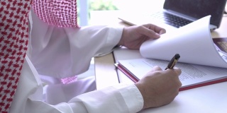 宽镜头阿拉伯人审查和签署文件