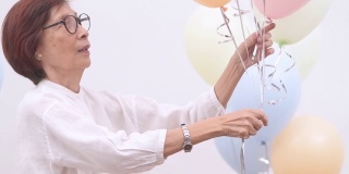 亚洲活跃的老年妇女用彩色气球庆祝生日