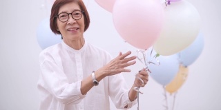 快乐的亚洲资深妇女与气球。老年人生日或周年聚会概念