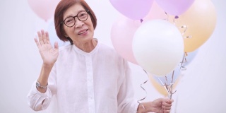 快乐的亚洲资深妇女与气球。老年人生日或周年聚会概念