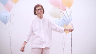亚洲活跃的高级妇女与彩色气球。快乐老人生活方式视频素材模板下载