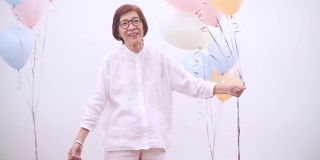 亚洲活跃的高级妇女与彩色气球。快乐老人生活方式