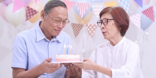 亚洲老夫妇拿着蛋糕在家庆祝生日。老年人在家里一起享受快乐时光。老年人家庭在家的概念。