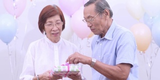 亚洲老夫妇拿着礼物在家庆祝生日。老年人在家里一起享受快乐时光。老年人家庭在家的概念。