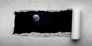 创造性的4k时间循环播放了一个在夜空中发光的满月和漂浮的云的视频，这是通过一个带有撕裂边缘的旧复古旧纸洞可以看到的。