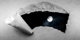 创造性的4k时间循环播放了一个在夜空中发光的满月和漂浮的云的视频，这是通过一个带有撕裂边缘的旧复古旧纸洞可以看到的。