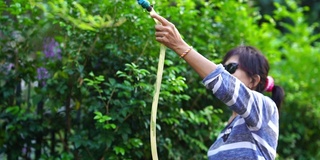 亚洲高级妇女淋浴植物在花园里