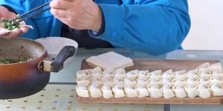 照片中，不明身份男子正在用手制作美味的自制饺子，馅料是碎肉和蔬菜。传统中餐，4k镜头，快动镜头。