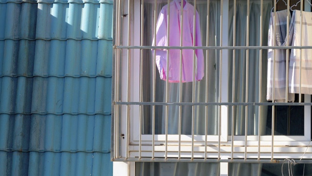 洗好的衣服在晴天挂在防盗窗上。中国典型的挂床单和挂衣服的生活方式。