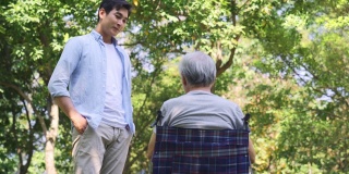 年轻的亚洲儿子在户外拜访年长的父亲并与之交谈