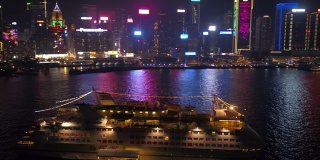 香港航拍v28低空飞过维多利亚港，周围是一艘小型游船，夜晚的城市风光一览无余。