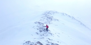 女性高山攀登者正在冬季攀登高海拔山脉的顶峰