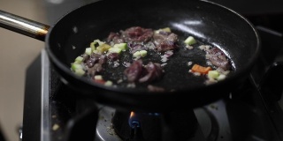 在厨房的煎锅里煎肉和蔬菜