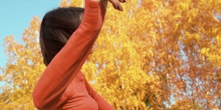 快乐的女人在秋天的公园跳舞。美丽的女人训练舞蹈在户外锻炼公园在桔子树的背景。健身妇女在城市公园训练编舞练习。